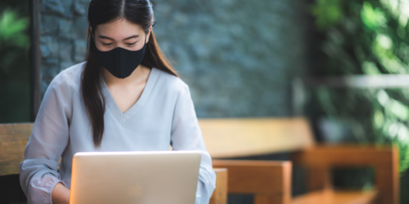 Woman wearing mask using laptop