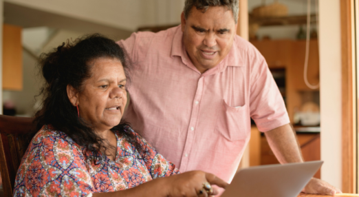 A First Nations woman and man looking at a laptop.