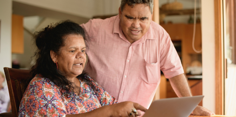 A First Nations woman and man looking at a laptop.