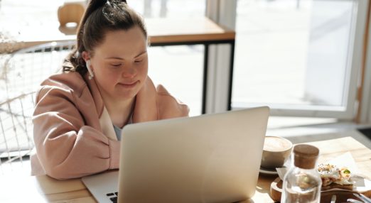 Woman with Down Syndrome using a laptop in a cafe.